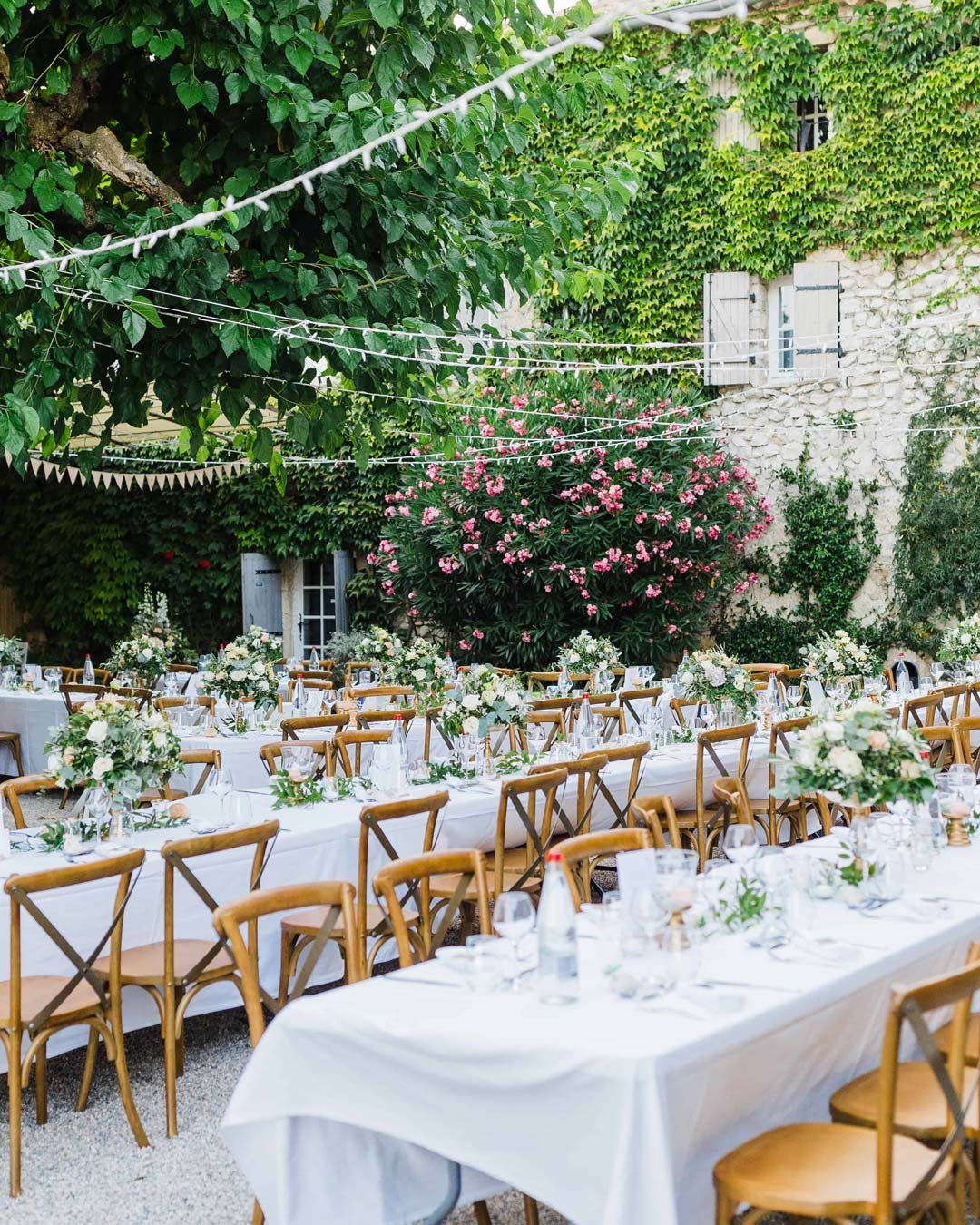 Tables de réception dressées dans la cour provençale de la Bastide de Lussan, grand mas en pierre authentique 