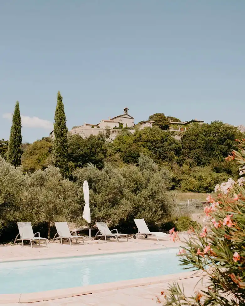 Vue sur la piscine et le village perché depuis la Bastide de Lussan